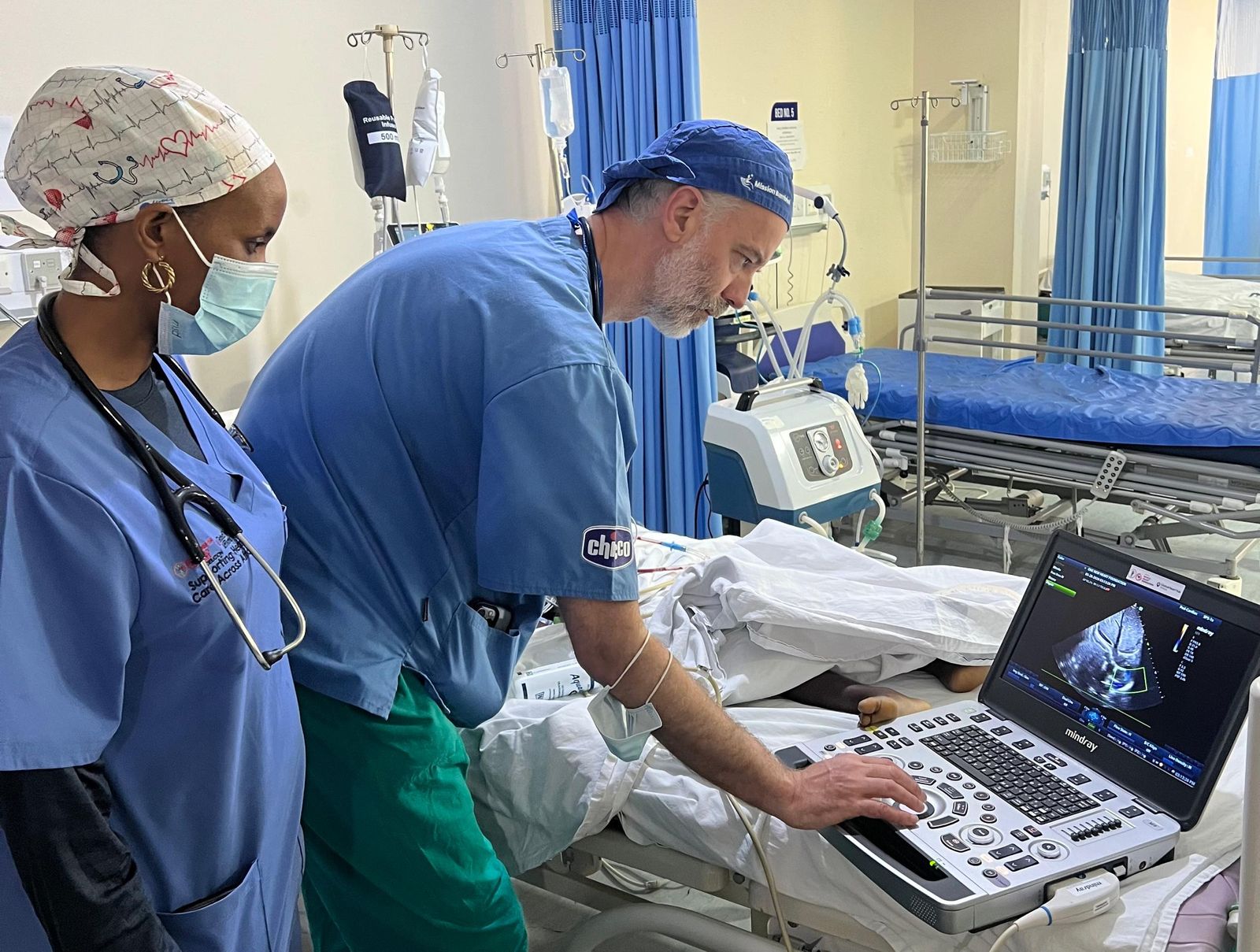 A visiting clinician demonstrates an echocardiogram while local clinicians observe