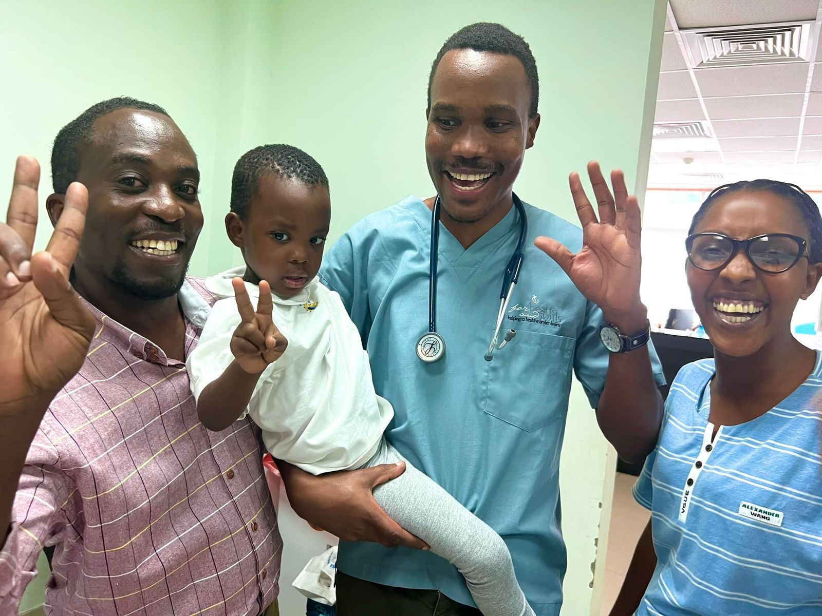 Clinicians and a caregiver celebrate with a child after treatment